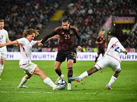 Germany's Emre Can (centre) is tackled by Belgium's Wout Faes (left) and Johan Bakayoko during the international friendly in Cologne, western Germany.