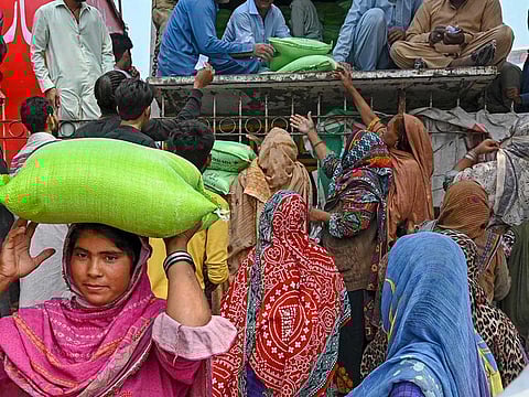 Women collect free bags of flour from a government distribution point in Lahore on April 2, 2023.