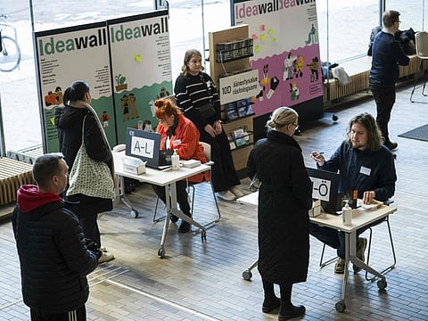 Voters queue to sign in to cast ballots at a polling center during the Finnish general elections, in Helsinki, on April 2, 2023.