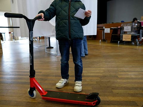 A person holds a ballot and an e-scooter during a municipal public "citizen vote" voting session on free-floating electric scooters at the city hall of the 17th district in Paris on April 2, 2023.