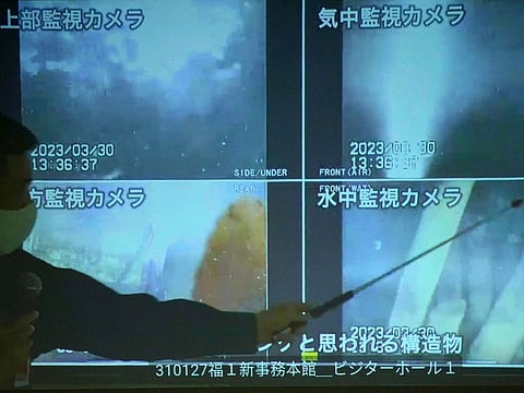 A spokesperson of the Tokyo Electric Power Company Holdings (TEPCO) shows photos captured by a robotic probe inside one of the three melted reactors at the tsunami-wrecked Fukushima nuclear power plant, during a news conference at the TEPCO headquarters in Tokyo, Tuesday, April 4, 2023.