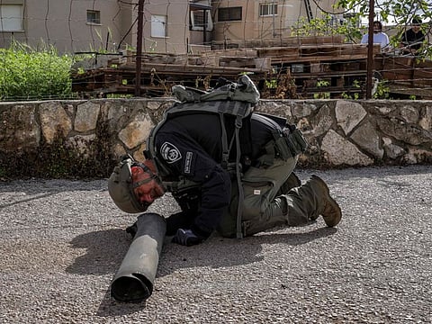An Israeli police bomb disposal unit member inspects the remains of a shell fired from Lebanon and intercepted by Israel in its northern town of Fassuta on April 6, 2023.