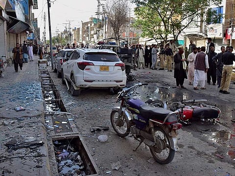 Police officers people gather at the site of a bomb blast, in Quetta, Pakistan, Monday, April 10, 2023.