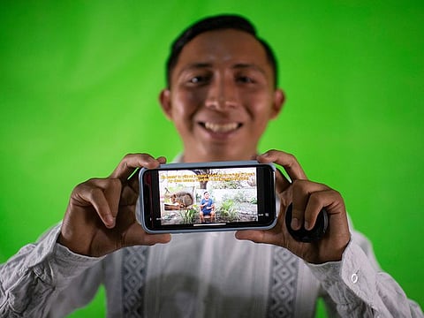 Mexican TikToker Santos Tuz poses for a photo in his studio while showing a video of himself spreading the Mayan language in Oxkutzcab, Yucatan State, Mexico.