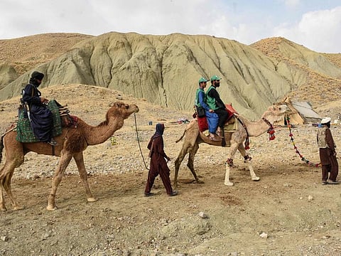 In this picture taken on March 23, 2023, a member of the levies tribal force (left) and census officials from the Pakistan Bureau of Statistics (right) ride camels to collect information from Marri tribespeople living in the remote mountainous area of Mawand as part of a national census in southwest Pakistans Kohlu district, Balochistan province.