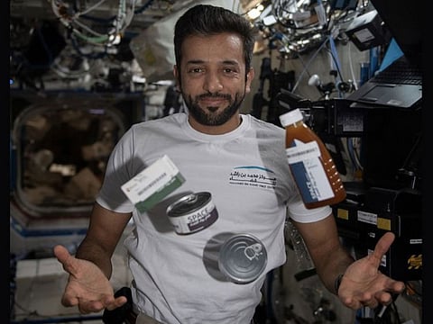 Al Neyadi juggling food canisters and packages onboard the International Space Station