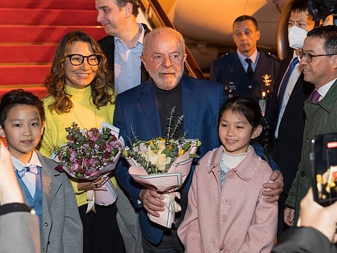 In this photo released by Xinhua News Agency, Brazilian President Luiz Inacio Lula da Silva, centre, and first lady Rosangela Silva, second left, receive flowers presented by children from the Shanghai Children's Palace of the China Welfare Institute upon arrival in Shanghai, China on Wednesday, April 12, 2023.