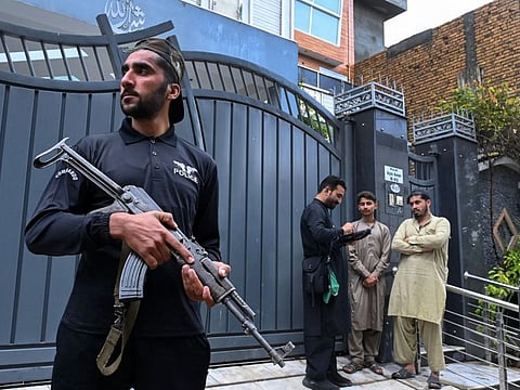 A security personnel stands guard next to an official from the Pakistan Bureau of Statistics using a digital device to collect information from residents during the first ever door-to-door digital national census in Peshawar, in Khyber Pakhtunkhwa province on March 25, 2023.