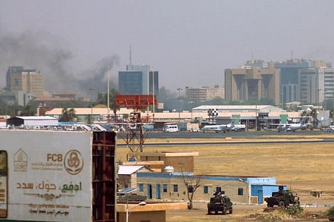 Military vehicles can be seen as smoke bellows above buildings in the vicinity of the Khartoum airport on April 15, 2023, amid clashes in the city.
