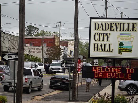 Community members watch as crime scene investigators work the scene of a shooting in Dadeville, Alabama.