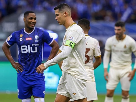 Al Nassr's Portuguese forward Cristiano Ronaldo (centre) walks past Al Hilal’s Odion Ighalo during the Saudi Pro League football match at the Prince Faisal Bin Fahd stadium in the capital Riyadh.