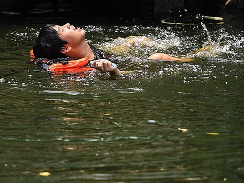 A man swims in a canal as temperatures hit a record 45.4 degrees Celsius (113.7 Fahrenheit) in Bangkok on April 22, 2023.