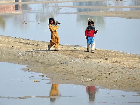 Internally displaced flood-affected girls walk beside the flood waters near a makeshift camp in the flood-hit area of Dera Allah Yar in Jaffarabad district of Balochistan province in Pakistan.