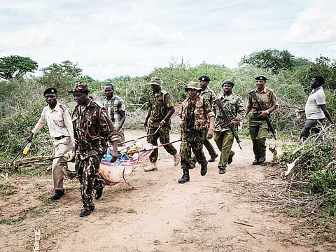 Security personnel carry a rescued young person from the forest in Shakahola, outside the coastal town of Malindi, on April 23, 2023.