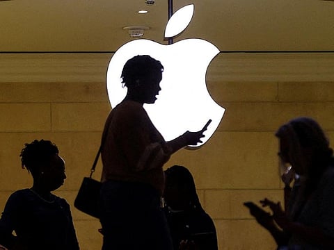 File photo: A women uses an iPhone mobile device as she passes a lighted Apple logo at the Apple store at Grand Central Terminal in New York City.