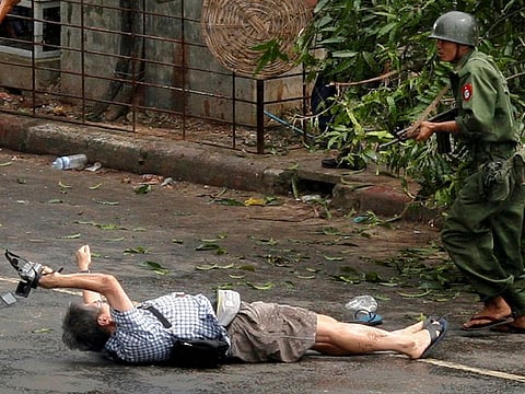 Kenji Nagai of APF tries to take photographs as he lies injured after police and military officials fired upon and then charged at protesters in Yangon's city centre September 27, 2007.