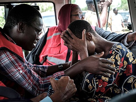 A member of the Kenyan Red Cross comforts a rescued follower of the the Good News International Church.