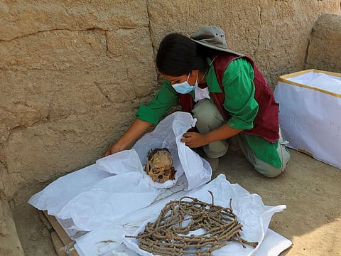 A worker wraps skeletal remains and parts of the funerary bundle of a mummy found by Peruvian archaeologists in the ruins of Cajarmarquilla, in the outskirts of Lima.