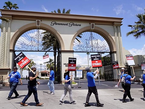 Members of the The Writers Guild of America West picket at an entrance to Paramount Pictures, Tuesday, May 2, 2023, in Los Angeles. The first Hollywood strike in 15 years began Tuesday as the economic pressures of the streaming era prompted unionized TV and film writers to picket for better pay outside major studios, a work stoppage that already is leading most late-night shows to air reruns. (AP Photo/Chris Pizzello)