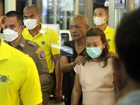 Sararat Rangsiwuthaporn, a suspect in over a dozen murders, is escorted by police officers at a police station in Bangkok, Thailand.