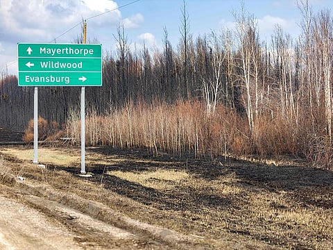A sign just off Highway 16 is pictured surrounded by burnt grass and trees in the Yellowhead County area, Alberta, Canada.