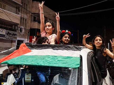 Palestinians and supporters of the Jihad militant group celebrate in the street after Palestenian factions and Israel reached a ceasefire agreement in Gaza City late on May 13, 2023.