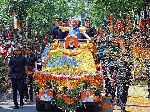 Prime Minister Narendra Modi waves while being showered with flower petals by the supporters during a roadshow for the Karnataka Assembly elections, in Bengaluru