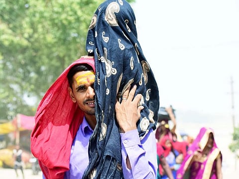 A man commutes covering his child on a hot summer day, in India's Prayagraj on Tuesday.