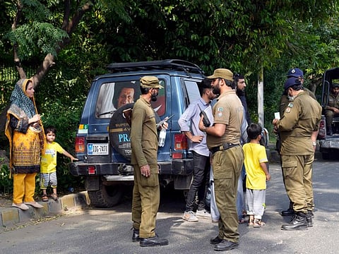 Police officers search a car at a temporary checkpoint around the home of Pakistan's former Prime Minister Imran Khan, in Lahore.