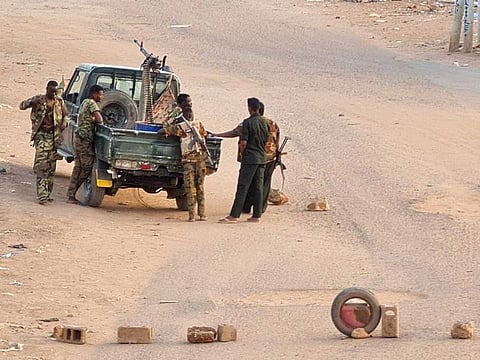 Soldiers of the Sudanese army stand near their vehicle on a road blocked with bricks in Khartoum on May 20, 2023.