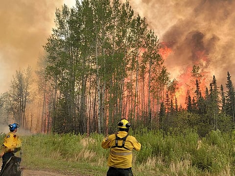 Firefighters watch the flames of SWF-063, part of the Grizzly Wildfire Complex, in East Prairie Metis Settlement, Alberta.