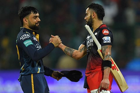Royal Challengers Bangalore's Virat Kohli (right) is greeted by Gujarat Titans' Rashid Khan.