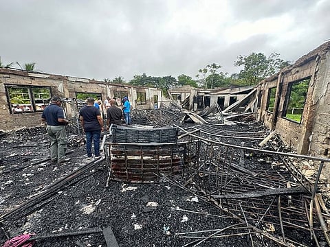 People stand inside the remains of a burnt secondary school dormitory after several children, most of them from indigenous communities, died after a fire gutted the building overnight, in Mahdia, Guyana.