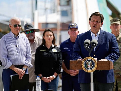 President Joe Biden listens as Florida Gov. Ron DeSantis speaks after they toured an area impacted by Hurricane Ian on Wednesday, Oct. 5, 2022, in Fort Myers Beach, Fla.