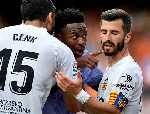 Real Madrid's Vinicius Junior (centre) gestures towards a fan after witnessing abuse as Valencia's Jose Gaya (right) and Cenk Ozkacar attempt to restrain him.