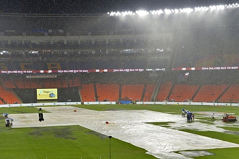 Ground staff cover the field during rains before the start of the IPL final between Gujarat Titans and Chennai Super Kings in Ahmedabad on Sunday.