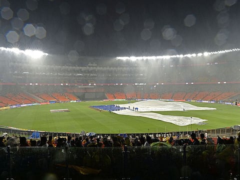 Ground staff cover the field as it rains during the Indian Premier League (IPL) Twenty20 final cricket match between Gujarat Titans and Chennai Super Kings at the Narendra Modi Stadium in Ahmedabad.