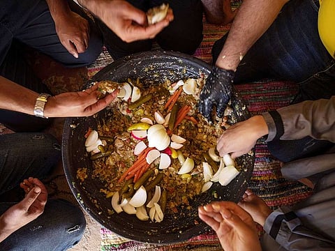 Palestinians eat 'Lasima,' a dish that is popular in the southern Gaza Strip but shunned in its north, at a garden in Khuzaa, Gaza Strip, Saturday, May 20, 2023.