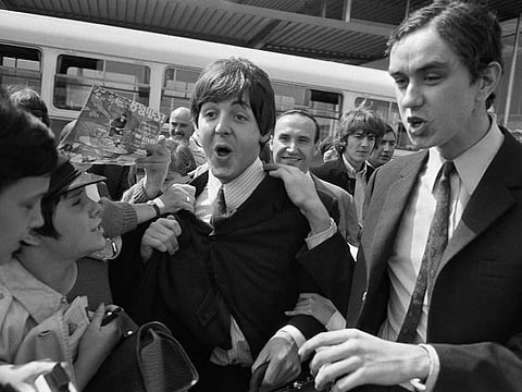 Fans surround Beatles Paul McCartney (C) and George Harrison (2R) upon their arrival at Orly airport on June 20, 1965.