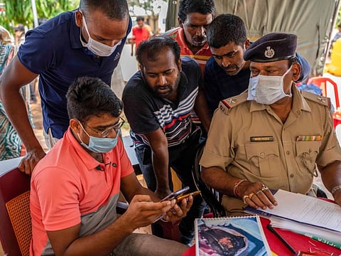 Relatives of victims of Friday's train accident try to identify their dear ones by looking at photographs on the phone of an official at the All India Institute of Medical Sciences hospital in Bhubaneswar in the eastern state of Orissa, India, Monday, June 5, 2023.