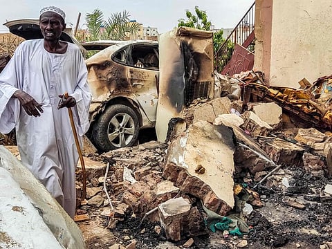 A man inspects damage as he walks through the rubble by a destroyed car outside a house that was hit by an artillery shell in the Azhari district in the south of Khartoum on June 6, 2023.
