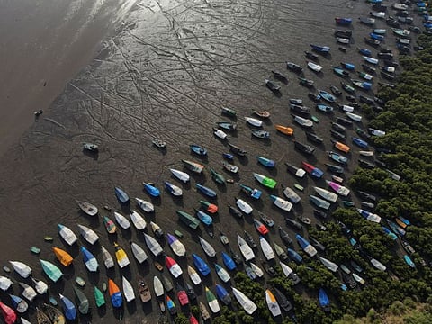 An aerial view of fishing boats covered with tarpaulin sheets parked on the shore, before the start of the monsoon season, on the outskirts of Mumbai, on June 8, 2023.