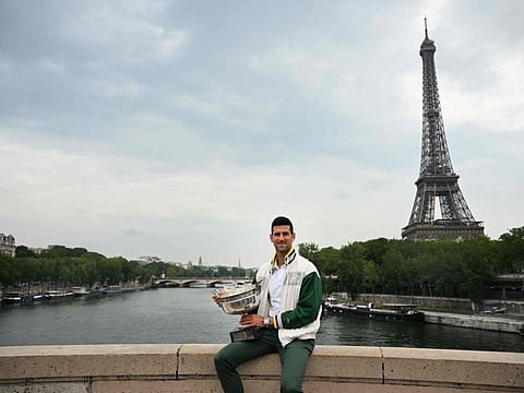 Serbia's Novak Djokovic poses with the Musketeers' Trophy, as the Eiffel Tower is seen in the background, during a photocall in Paris on Monday.