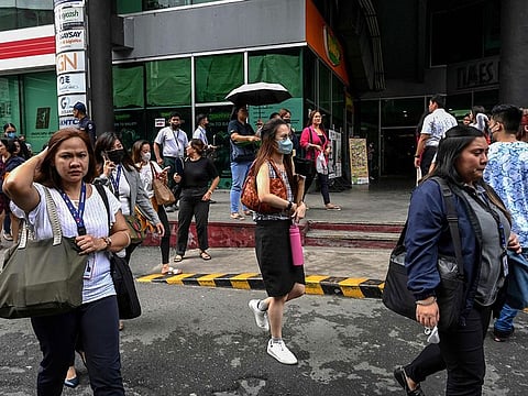 People gather on a street after evacuating a building in Manila on June 15, 2023, following a magnitude 6.3 earthquake struck the Philippines.