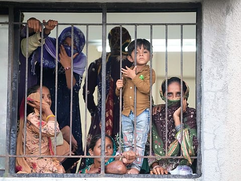 People evacuated from a village near Jakhau look out from a window at a shelter at Naliya, Kutch district, India, Wednesday, June 14, 2023. Cyclone Biparjoy is projected to make landfall near Jakhau port. The cyclone forecast to slam ashore on Thursday is expected to be the most powerful to hit western India and Pakistan since 2021. (AP Photo/Ajit Solanki)