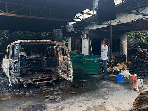 A man stands next to a burnt vehicle at the ransacked residence of Minister of State for External Affairs Rajkumar Ranjan Singh in Imphal on June 16, 2023.