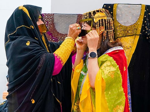 A Korean visitor (right) at Sharjah's pavilion at Seoul book fair tries on traditional Emirati attire