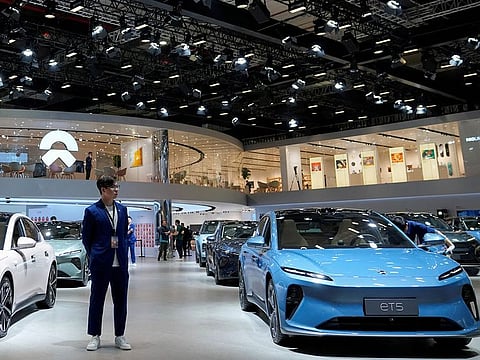 A staff member stands near Nio ET5 cars at its booth at the Auto Shanghai show, in Shanghai, China. File photo taken on April 18, 2023.