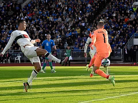 Portugal's forward Cristiano Ronaldo scores past Iceland's goalkeeper Runar Runarsson during the Euro 2024 Group J qualification match in Reykjavik on Tuesday.