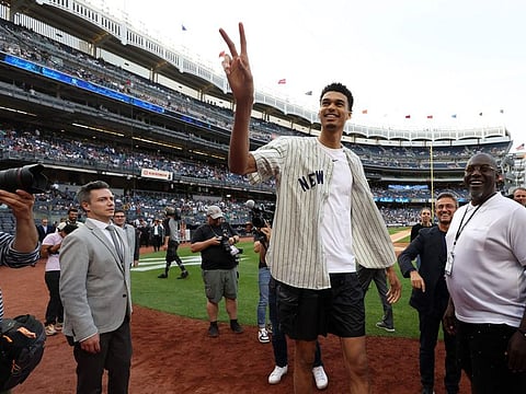 Victor Wembanyama tosses the ball to fans in the crowd after throwing out the ceremonial first pitch prior to the game between the Seattle Mariners and the New York Yankees at Yankee Stadium.